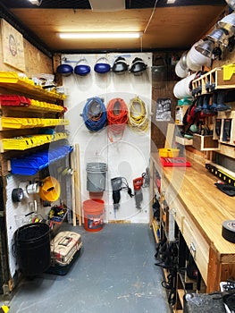 Organized shop storage area featuring bins of small parts, safety helmets, and cords wrapped up.