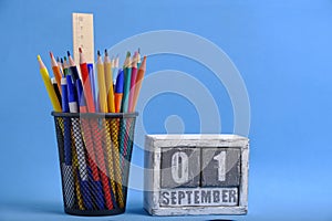 Organizer with pencils and ruler, stationery stand and wooden calendar with date September 01 blue background.