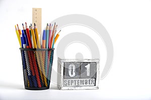 Organizer with pencils and ruler, stationery stand and wooden calendar with date September 01, white background.