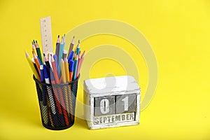 Organizer with pencils and ruler, stationery stand and wooden calendar with date September 01 yellow background.