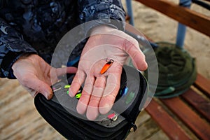 Organizer with a set of artificial lures for fishing in the hands of a fisherman.