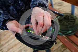 Organizer with a set of artificial lures for fishing in the hands of a fisherman.