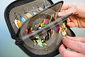 Organizer with a set of artificial lures for fishing in the hands of a fisherman.