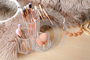 Organizer with set of professional makeup brushes and accessories on wooden table