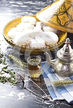 Oriental Algerian sweet cookies kaab el ghazal, tea cup and pot and mint leaves. photo