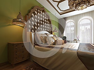 Oriental bedroom in Arab style, with a wooden headboard and green walls. TV unit, dressing table, armchair with coffee table