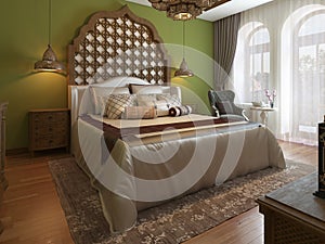 Oriental bedroom in Arab style, with a wooden headboard and green walls. TV unit, dressing table, armchair with coffee table