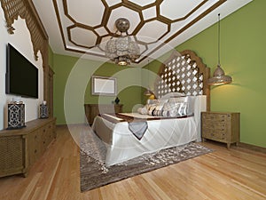 Oriental bedroom in Arab style, with a wooden headboard and green walls. TV unit, dressing table, armchair with coffee table