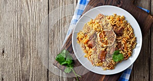 Oriental cuisine. Uzbek pilaf or plov from rice and meat. Wooden rustic background.