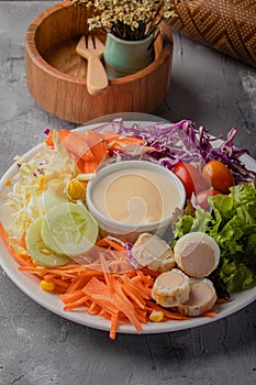 Oriental food Brightly colored vegetable salad, prune tomatoes, lettuce, corn and cheese in a white plate on a gray table