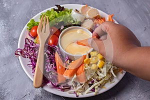 Oriental food Brightly colored vegetable salad, prune tomatoes, lettuce, corn and cheese in a white plate on a gray table