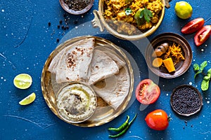 Oriental food Indian paneer sabji with chapati and chutney sous. indian cuisine. Indian Curry in copper brass with ingredients in