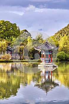 Oriental pavilion reflected in water at sunset, Lijiang, China.