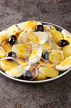 Oriental salad is a favorite of Romanians potato salad with onions, olives and boiled eggs close-up on a plate. Vertical