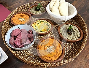 Oriental specialties starter, also known as mezze, with various dips. Hummus, muhammara, baba ghanoush and pita bread.