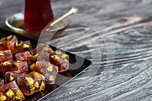 Oriental sweets with different nuts a glass of tea and a spoon. Eastern sweets. Traditional Turkish delight Rahat lokum on a