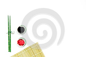 Oriental table set up with bamboo sticks for sushi and maki, soy sauce on white background top view space for text