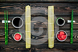 Oriental table set up with bamboo sticks for sushi and maki, soy sauce on wooden background top view