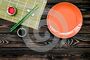 Oriental table set up with plate and bamboo sticks for sushi and maki on wooden background top view space for text