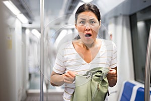 Oriental woman amazed by theft from her bag in subway car