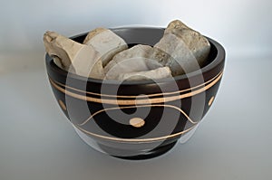 Oriental wood bowl with notches white stones inside on white background