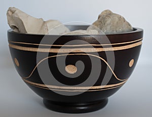 Oriental wood bowl with notches white stones inside on white background