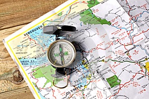 An orientation compass rest on a wooden table with a geographic map and copy space for your text