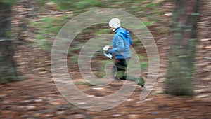 Orienteering. Motion blur. A young girl athlete with a sports card in his hand quickly runs along the orienteering course in the