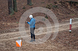 Orienteering. A young girl athlete stands near a checkpoint with a map and determines where to run next