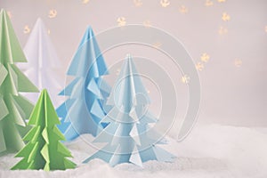 Origami 3D Xmas tree from paper on white background and bokeh lights. Merry Christmas and New Year card. Paper art style. Copy spa
