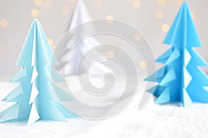 Origami 3D Xmas tree from paper on white background and bokeh lights. Merry Christmas and New Year card. Paper art style. Copy spa