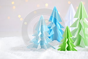 Origami 3D Xmas tree from paper on white background and bokeh lights. Merry Christmas and New Year card. Paper art style. Copy spa