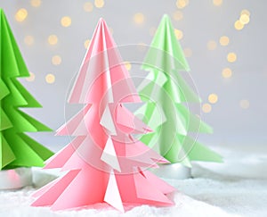 Origami 3D Xmas tree from paper on white background and bokeh lights. Merry Christmas and New Year card. Paper art style. Copy spa