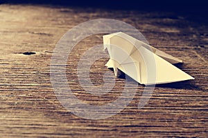 Origami bird on a wooden surface, retro effect