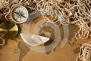 Origami boat on vintage world map. Travel concept