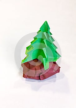 Origami Christmas tree with green paper stay on the rock with br