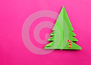 Origami Christmas tree paper on pink background.