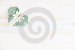Origami heart of banknote. Origami made of a dollar bill on light wooden background, copyspace for text