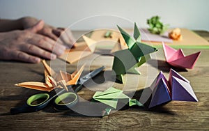 Origami making - figures and hands on wooden table.