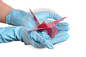 Origami paper crane in hand with rubber gloves