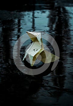 Origami paper figure on the background of a gloomy city street and puddles