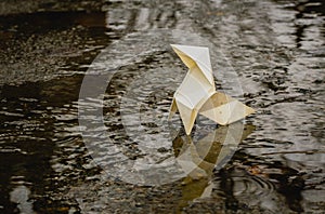 Origami paper figure on the background of a gloomy city street and puddles photo