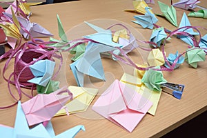 Origami paper folding activities in progress showing finished colored paper folds