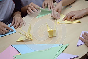 Origami paper folding activities in progress showing hands folding colored papers