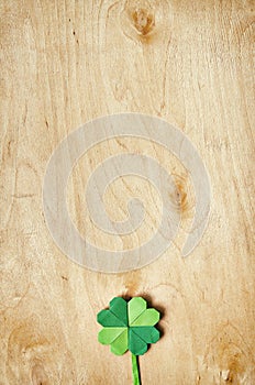 Origami paper green clover shamrock leaf on light plywood background