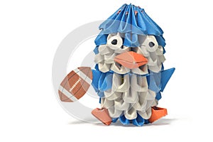 An origami penguin lays with a football.