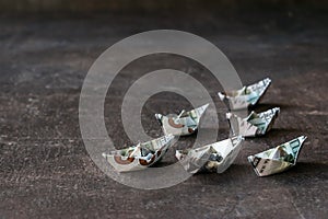 Origami ships from US dollars on a dark background. Many boat do
