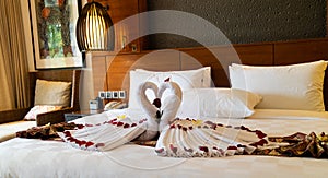 Origami swans made out of towels and laid out on a bed in a honeymoon suite