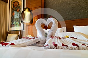 Origami swans made out of towels and laid out on a bed in a honeymoon suite