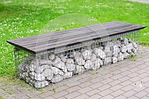 Original bench in public park upholstered with artificial grass supported by original stones